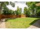 Large, grassy backyard is bordered by a tall wood fence and mature trees for privacy and shade at 9861 E Ohio Ave, Denver, CO 80247