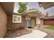 Charming brick home featuring a covered entryway with a light blue front door and manicured landscaping at 9861 E Ohio Ave, Denver, CO 80247