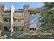 Multi-story condo building with stone accents, balconies, and mature trees in a landscaped community at 3365 Chisholm Trl # B102, Boulder, CO 80301