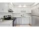 Well-lit kitchen boasts sleek white cabinetry, stainless steel appliances, and a tiled backsplash at 3365 Chisholm Trl # B102, Boulder, CO 80301