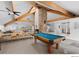 Open recreation room with a billiards table, vaulted ceilings, exposed beams and a stone fireplace at 3365 Chisholm Trl # B102, Boulder, CO 80301