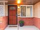 Inviting front porch featuring a security door, vibrant potted flowers, and a brick facade at 3555 Leyden St, Denver, CO 80207