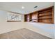 Finished basement area with carpet, built-in wooden shelving, and a window for natural light at 9374 W Friend Dr, Littleton, CO 80128