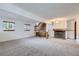 Open basement with carpet, brick fireplace, exposed staircase, and natural light at 9374 W Friend Dr, Littleton, CO 80128