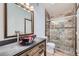Bathroom featuring tiled shower and a unique decorative glass bowl sink on a wooden vanity at 9374 W Friend Dr, Littleton, CO 80128