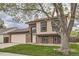 Two story house with light brick, large tree, and manicured lawn on an overcast day at 9374 W Friend Dr, Littleton, CO 80128