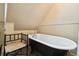 Classic bathtub with a vintage faucet and a cozy chair, nestled under a wallpapered, sloped ceiling at 916 Griffith St, Georgetown, CO 80444