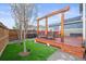 Landscaped backyard features a wooden pergola, artificial turf, and a spacious deck perfect for entertaining at 7903 E 50Th Dr, Denver, CO 80238