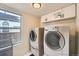 Functional laundry room with washer, dryer, storage cabinets, and a window at 4567 Flanders Way, Denver, CO 80249