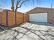 Exterior view of a garage with a white door and a wooden fence in a brick residential area at 2995 Albion St, Denver, CO 80207