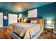 A main bedroom featuring an upholstered bed with a lavish comforter and dark teal colored walls at 1152 S Yosemite Way # 29, Denver, CO 80247