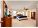 Spacious main bedroom featuring neutral carpet, ceiling fan, and a view into the main bathroom at 7083 Leopard Dr, Lone Tree, CO 80124