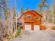 Beautiful wooden home with attached two-car garage nestled among trees and set back from the driveway at 30813 Kings Valley Dr, Conifer, CO 80433