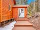 Charming front entrance features a covered porch, wooden steps, and a white door with a decorative wreath at 30813 Kings Valley Dr, Conifer, CO 80433