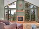 Comfortable living room with a fireplace, large windows, and scenic views of surrounding trees at 30813 Kings Valley Dr, Conifer, CO 80433