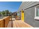 A close up on the front porch deck, yellow front door, and exterior details at 695 S Quitman St, Denver, CO 80219