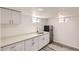 Basement kitchenette features white cabinets, quartz counters, stainless mini fridge, and stylish gray wood-look floors at 695 S Quitman St, Denver, CO 80219