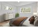 Bright bedroom with two windows, neutral walls, wood laminate flooring, and a comfortable bed at 2621 S Federal Blvd, Denver, CO 80219