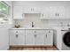 Bright laundry area featuring shaker cabinets, contrasting hardware, and modern machines at 2621 S Federal Blvd, Denver, CO 80219