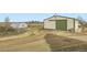 Barn and greenhouses with farmland in the distance under a clear sky at 49950 Oak Park Dr, Bennett, CO 80102