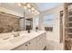 Bright bathroom featuring double vanity, glass block, tile surround and tile floor at 49950 Oak Park Dr, Bennett, CO 80102