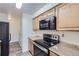 Modern kitchen with black appliances, light countertops, and light wood cabinets at 62 Newark St # D, Aurora, CO 80012