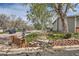 Street view of a condo complex with brick wall entrance, mature trees and manicured landscaping at 4028 Ames St, Wheat Ridge, CO 80212