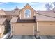 Charming home featuring two-car garage, tan siding, beautiful tiled roof, and lovely arched window above the garage at 5976 S Jellison St # E, Littleton, CO 80123