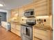 Modern kitchen features stainless steel appliances, wood cabinets, granite countertops, and tile backsplash at 5976 S Jellison St # E, Littleton, CO 80123