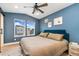 Bedroom featuring a blue accent wall, ceiling fan, and natural light from dual windows at 7808 W 43Rd Pl, Wheat Ridge, CO 80033