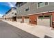 View of row of garages with neutral doors and brick accents on townhomes at 7808 W 43Rd Pl, Wheat Ridge, CO 80033