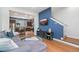Open-concept living room featuring a blue accent wall, television, hardwood floors and a view into the adjacent kitchen at 7808 W 43Rd Pl, Wheat Ridge, CO 80033