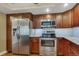 A well-lit kitchen featuring stainless steel appliances, wooden cabinetry, and granite countertops at 13961 E Marina Dr # 314, Aurora, CO 80014