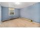 Bedroom with wood flooring, blue walls, a window, and baseboard heating throughout the room at 4635 Teller St, Wheat Ridge, CO 80033
