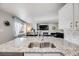 Bright kitchen features granite counters, stainless sink and a view into the living room with fireplace at 11727 Oswego St, Commerce City, CO 80640