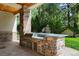 Covered outdoor kitchen with a built-in grill, stone countertops, and convenient storage in a backyard setting at 2 Viking Dr, Englewood, CO 80113