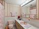 Retro pink bathroom featuring a coordinated sink, toilet, and patterned wallpaper at 3018 S Depew St, Denver, CO 80227