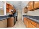 Galley kitchen with dark countertops, stainless steel appliances, and blond wood cabinets at 2880 S Locust St # 708S, Denver, CO 80222