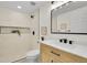 Modern bathroom with white cabinets, quartz countertop, walk-in shower, and decorative mirror at 1189 Lodgepole Dr, Evergreen, CO 80439