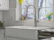 Close-up of a white farmhouse sink and faucet underneath a window in this updated kitchen at 2755 Geneva St, Denver, CO 80238