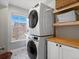 Functional laundry room with a stacked washer/dryer unit, floating shelves, and stylish flooring at 2755 Geneva St, Denver, CO 80238