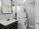 Cozy laundry room with stackable washer and dryer, complemented by a modern vanity and stylish mirror at 2755 Geneva St, Denver, CO 80238