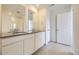 Bathroom with dual sinks, sleek countertops, vanity with cabinets, and a glass-enclosed shower at 7293 Waterleaf Trl, Littleton, CO 80125