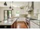 Well-lit open kitchen featuring an island with stools, stainless steel appliances, and custom cabinets at 2990 Osceola St, Denver, CO 80212