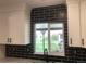 Modern kitchen features black subway tile backsplash and bright window with a view to the backyard at 10751 W 66Th Ave, Arvada, CO 80004