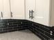 A renovated kitchen with white cabinets, black subway tile backsplash, and stone countertops at 10751 W 66Th Ave, Arvada, CO 80004