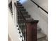 Carpeted staircase featuring dark wood railing and black iron balusters, offering a blend of style at 10751 W 66Th Ave, Arvada, CO 80004