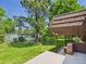 Backyard view showing a large tree, lush lawn, and a tennis court beyond the patio at 3957 S Peach Way, Denver, CO 80237