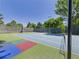 Full tennis court including basketball hoop and new netting. The multi-color court is surrounded by trees and a fence at 3957 S Peach Way, Denver, CO 80237