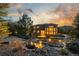 Stunning backyard at twilight, featuring a flowing water feature, mature trees, and a beautifully landscaped yard at 20148 E Windy Pine Pl, Parker, CO 80134